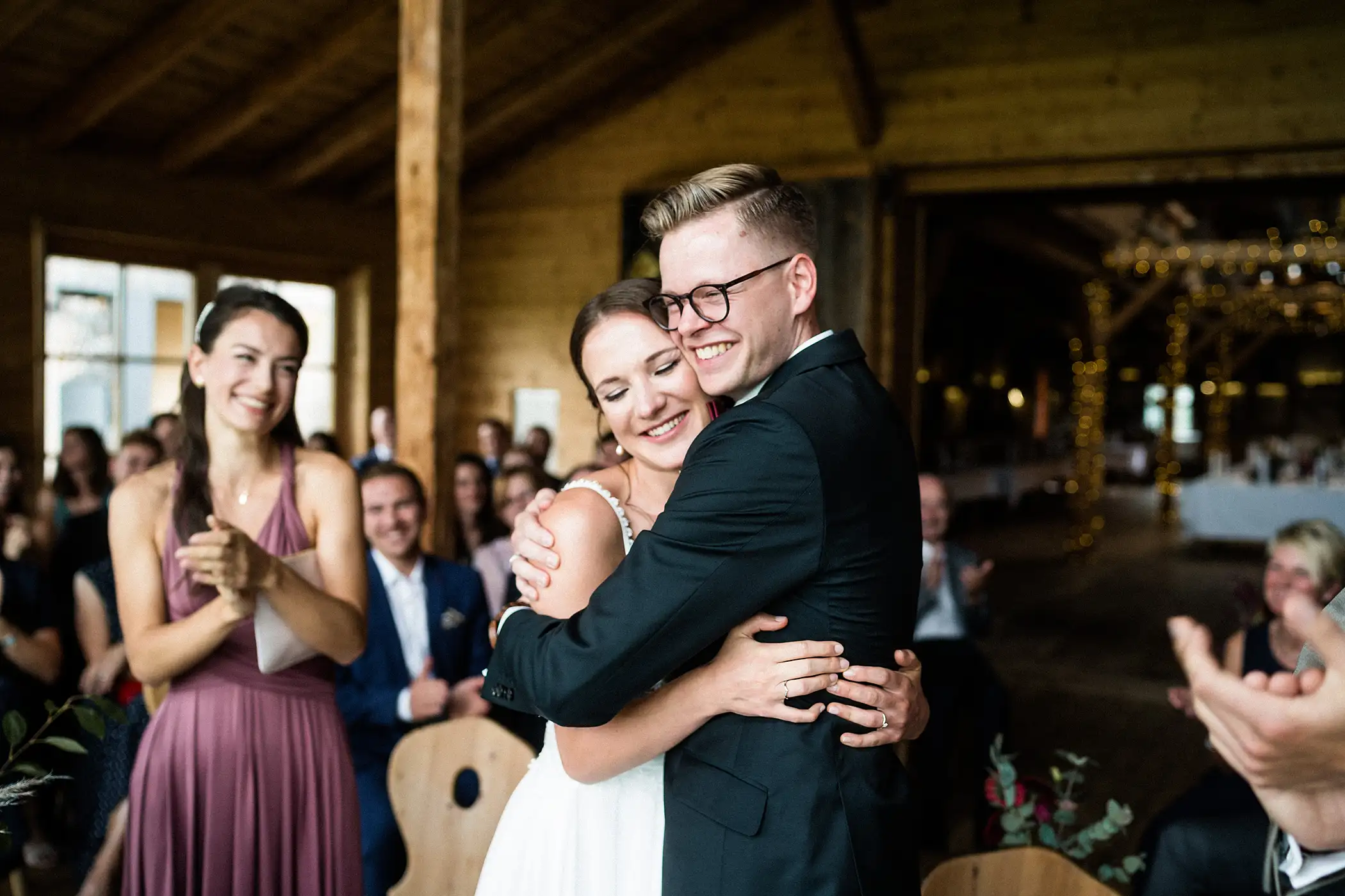 Brautpaar umarmt sich strahlend, umgeben von applaudierenden Gästen bei Hochzeit in den Lenderstuben Balzhausen. Fotografiert vom Hochzeitsfotograf aus Ulm