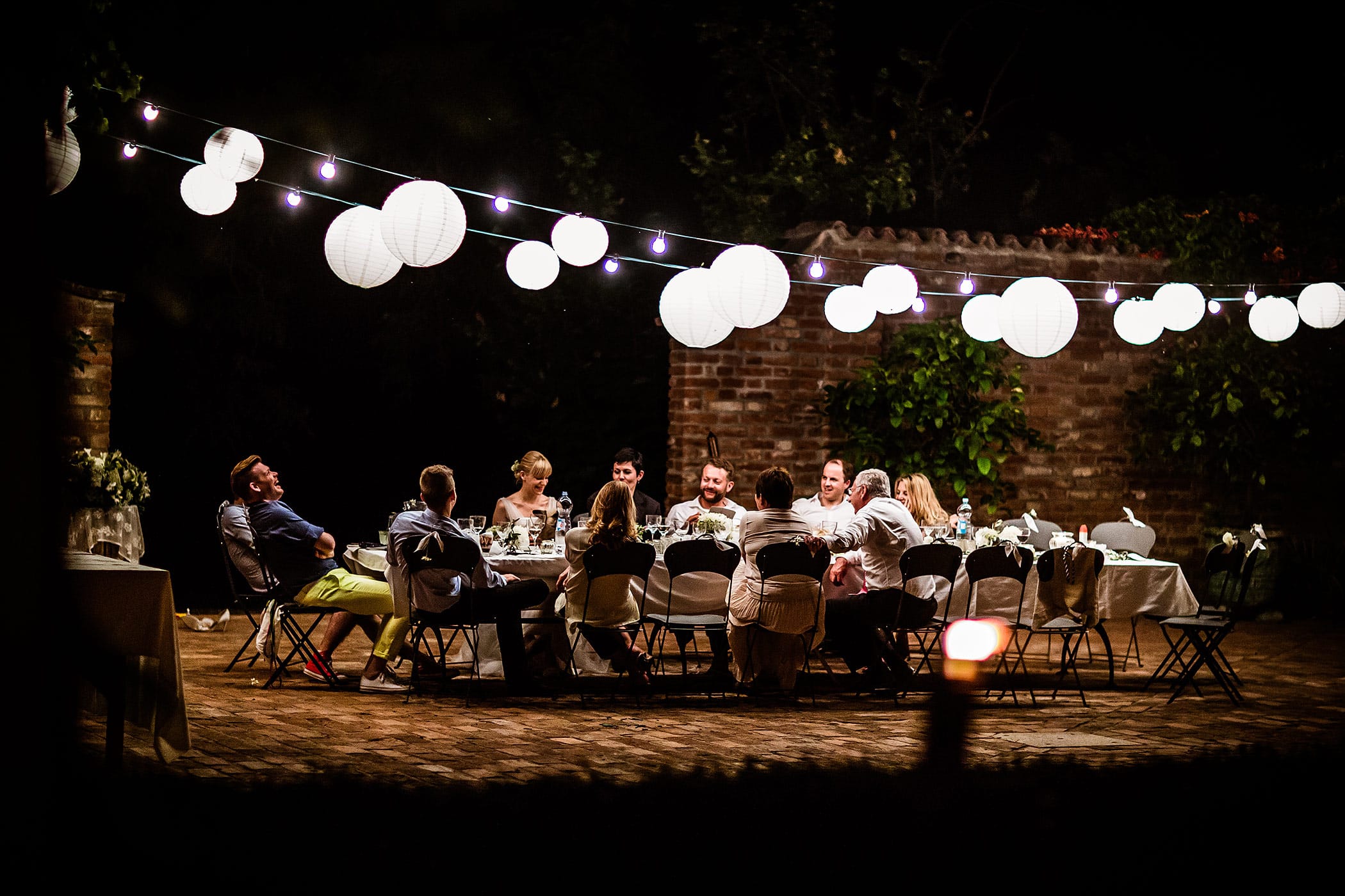 Abendliche Hochzeitsfeier in der Lombardei mit Lichterketten und festlicher Tafel im Freien, fotografiert von Hochzeitsfotograf