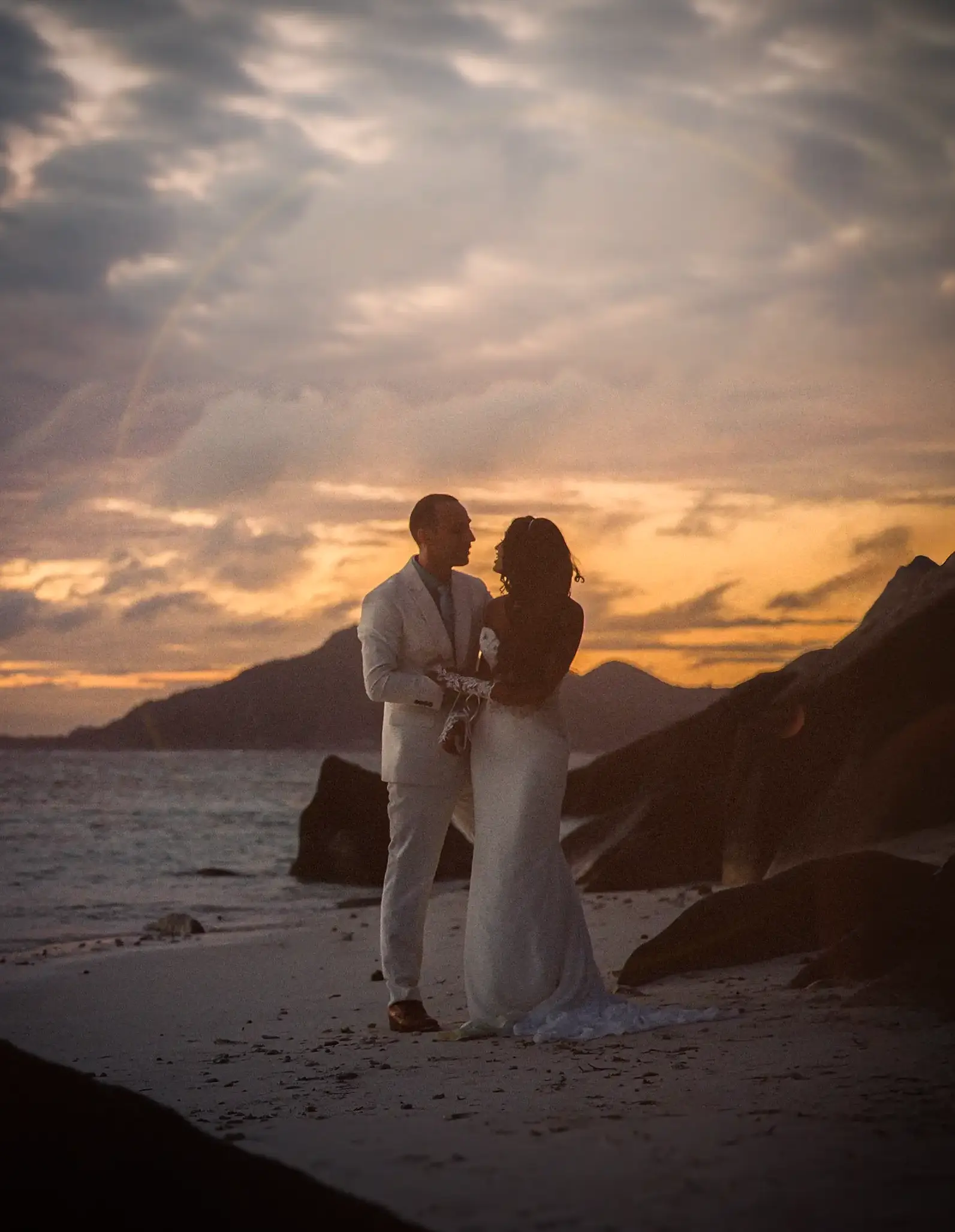 Hochzeitsfotograf auf den Seychellen begleitet Brautpaar bei Sonnenuntergang am Strand bei Fotoshooting