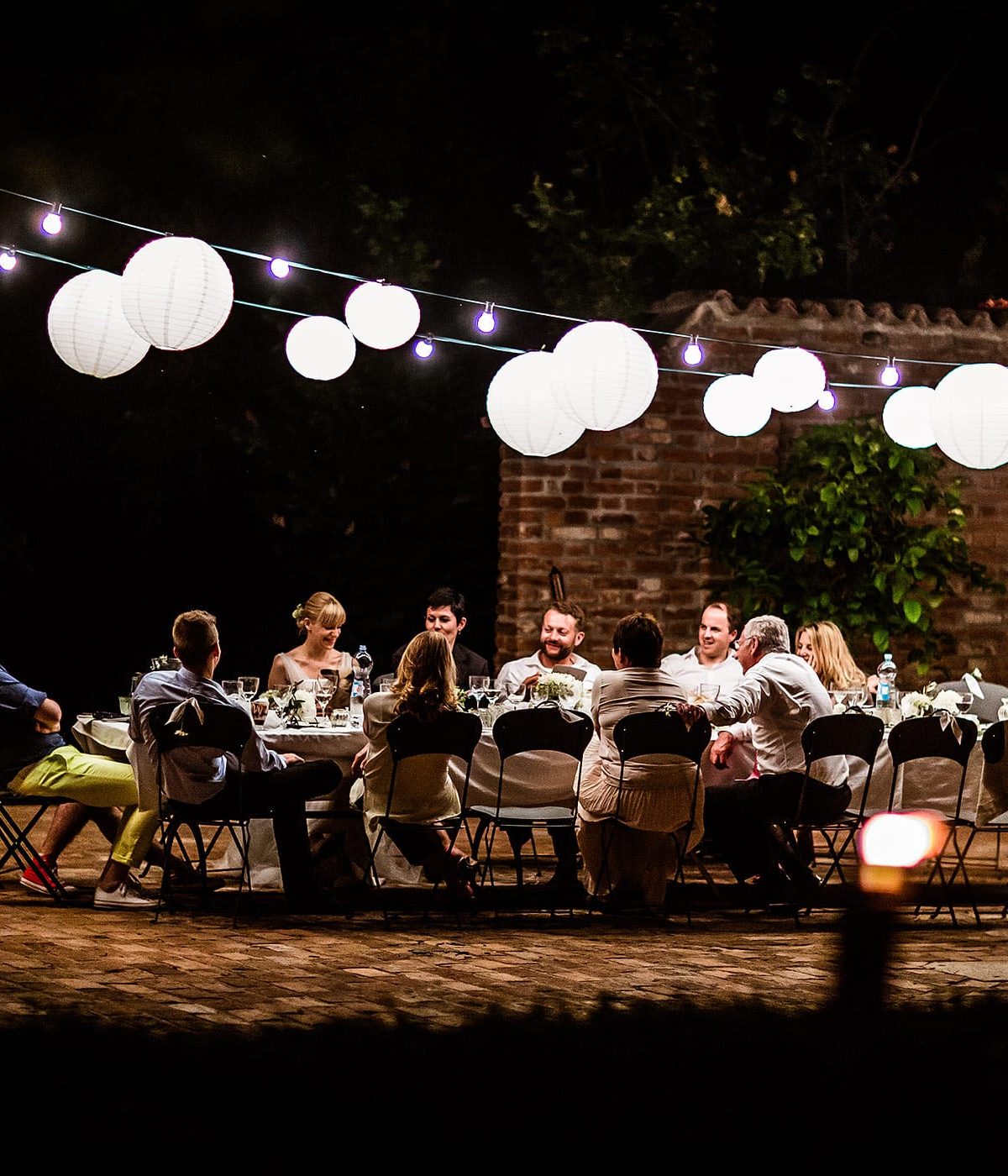 Abendliche Hochzeitsfeier in der Lombardei mit Lichterketten und festlicher Tafel im Freien, fotografiert von Hochzeitsfotograf