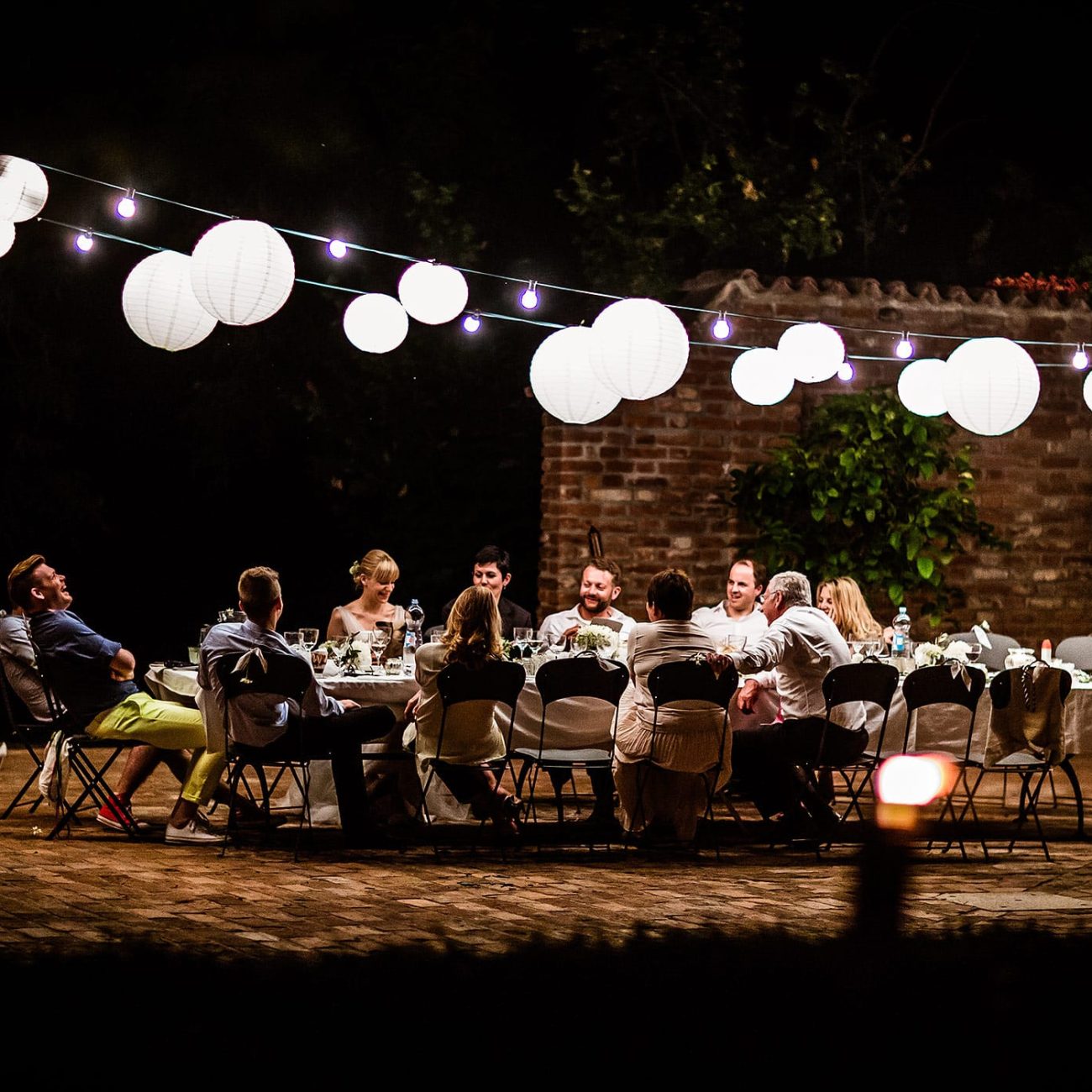 Abendliche Hochzeitsfeier in der Lombardei mit Lichterketten und festlicher Tafel im Freien, fotografiert von Hochzeitsfotograf
