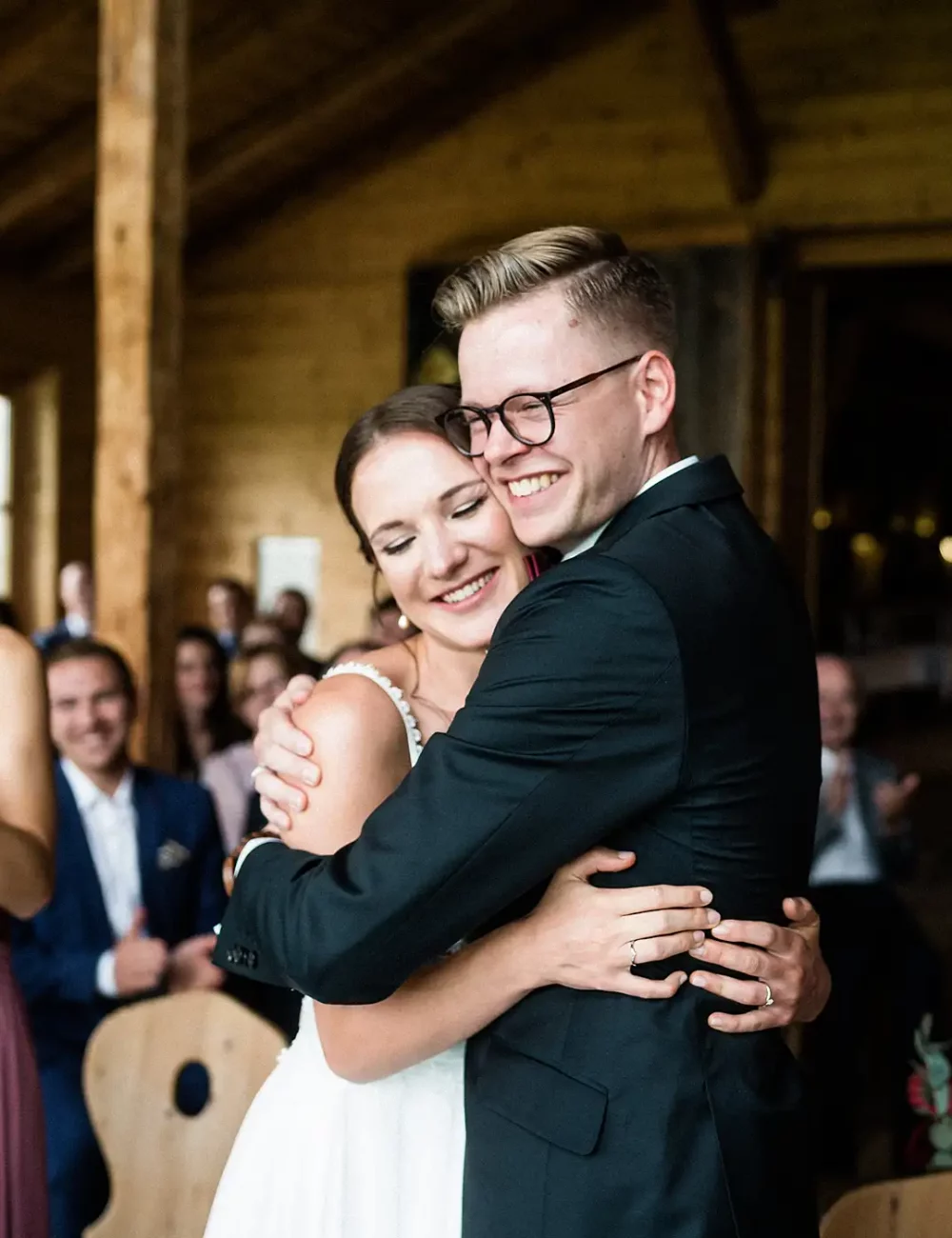 Brautpaar umarmt sich strahlend, umgeben von applaudierenden Gästen bei Hochzeit in den Lenderstuben Balzhausen. Fotografiert vom Hochzeitsfotograf aus Ulm